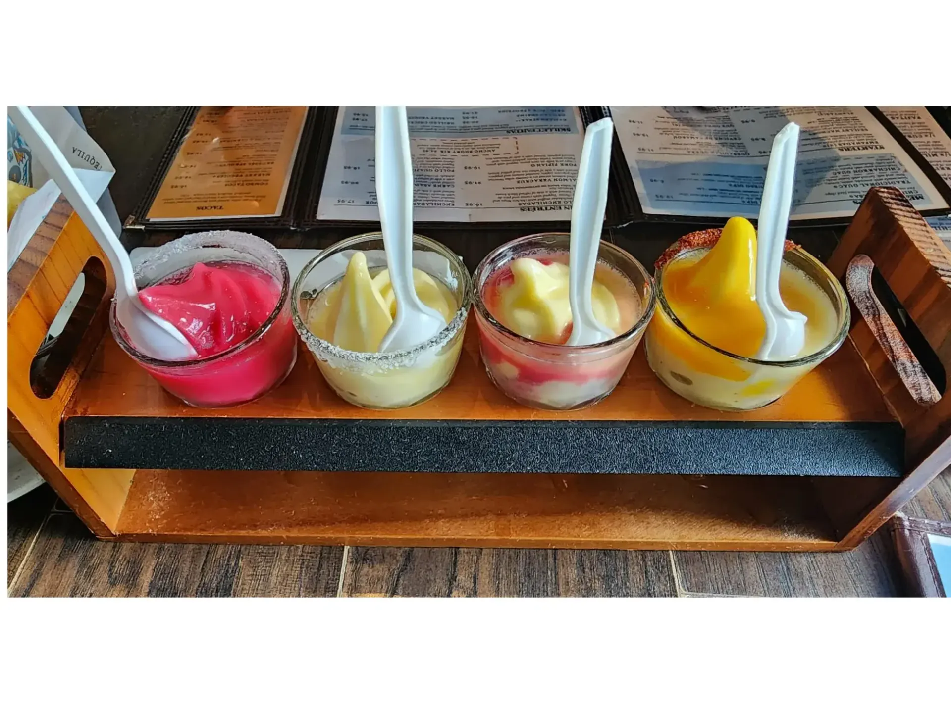Frozen margarita flight with mango, pomegranate, lime, and swirl flavors on a tasting tray.