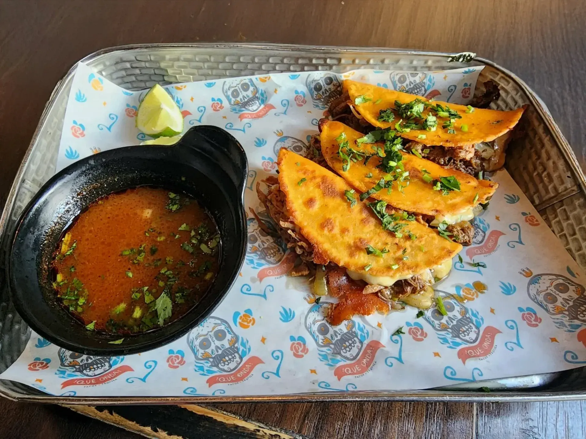 Birria tacos (quesabirria) with consommé for dipping three tacos on a tray
